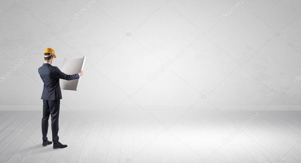 Architect standing in an empty space and holding a plan
