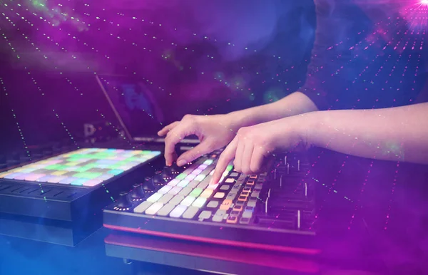 Mezcla de música a mano en el controlador dj con colores del club de fiesta alrededor — Foto de Stock