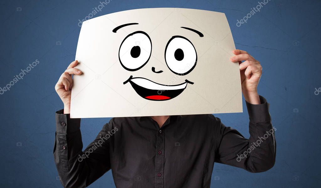 Student holding a paper with laughing emoticon in front of his face