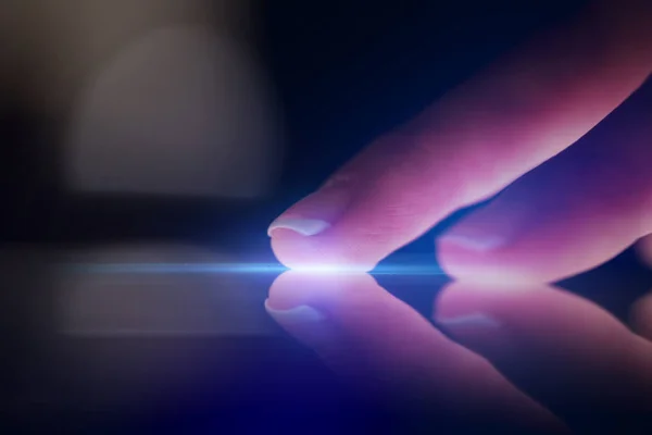Finger touching tablet with dark background