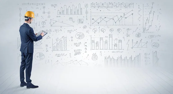 Engenheiro segurando um plano e de pé com gráficos, gráficos e relatórios em segundo plano — Fotografia de Stock