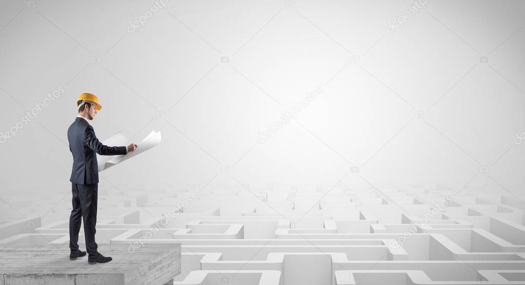 Architect standing on top of a maze and holding a plan