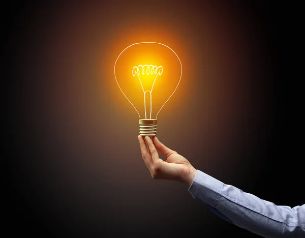 Hand holding light bulb on dark background — Stock Photo, Image