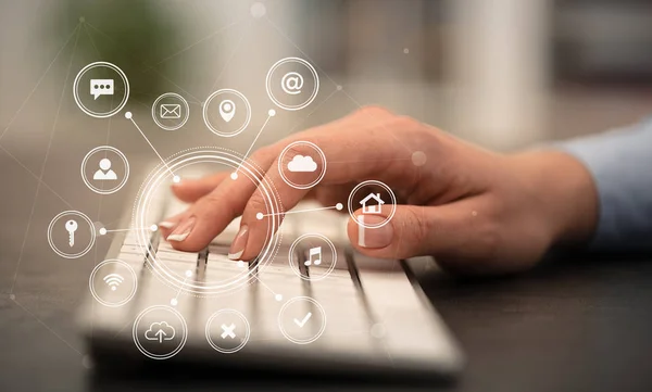 Hand typing on keyboard with application icons around — Stock Photo, Image