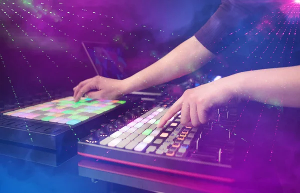 Mão misturando música no controlador dj com as cores do clube de festa ao redor — Fotografia de Stock