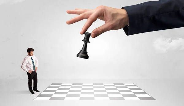 Маленький бизнесмен играет в шахматы с большой рукой — стоковое фото