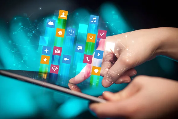 Mano usando tableta con iconos de aplicación volando alrededor — Foto de Stock
