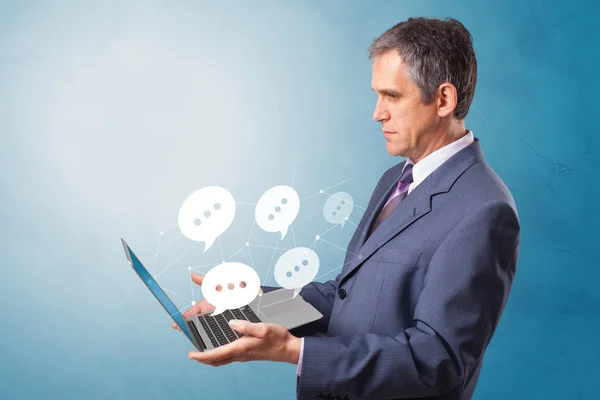 Man holding laptop with speech bubbles — Stock Photo, Image