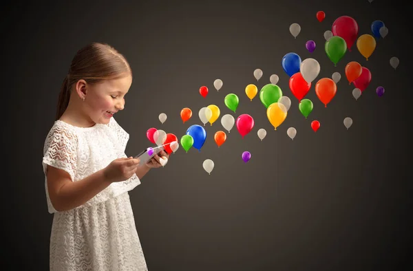 Girl holding tablet with colourful balloons around — Stock Photo, Image