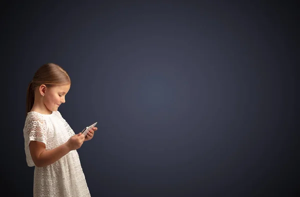 Nettes kleines Mädchen mit Tablet mit dunklem Hintergrund — Stockfoto