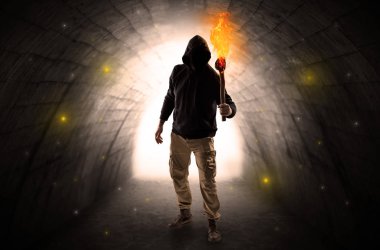 Karanlık bir tünelde flambeau yanma ile yürüyen adam