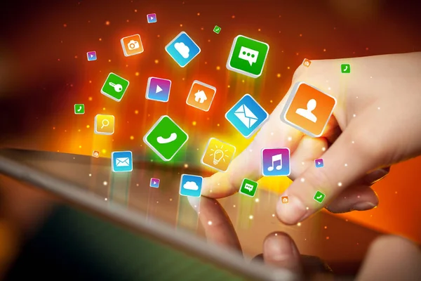 Main en utilisant une tablette avec des icônes d'application volant autour — Photo