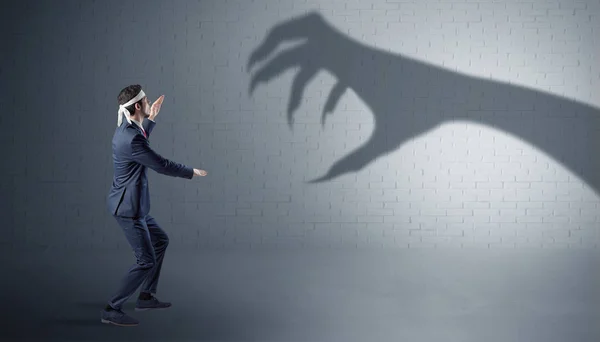 Empresário lutando com sombra de mão assustadora — Fotografia de Stock