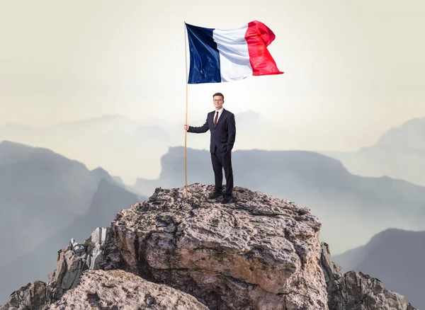 Businessman on the top of a rock holding flag — Stock Photo, Image