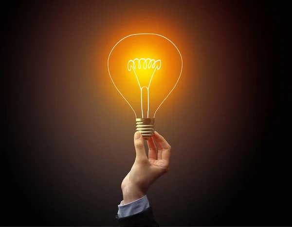 Hand holding light bulb on dark background — Stock Photo, Image