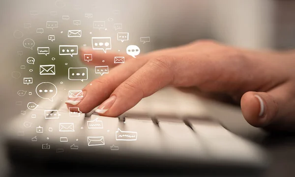 Hand typing on keyboard with chat icons around — Stock Photo, Image