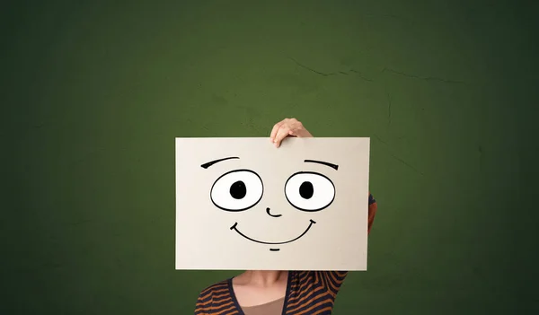 Student holding a paper with laughing emoticon in front of his face — Stock Photo, Image