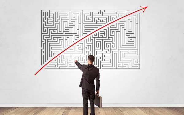 Businessman looking to a maze on a wall — Stock Photo, Image