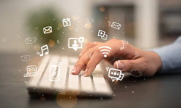 Hand typing on keyboard with application icons around — Stock Photo, Image