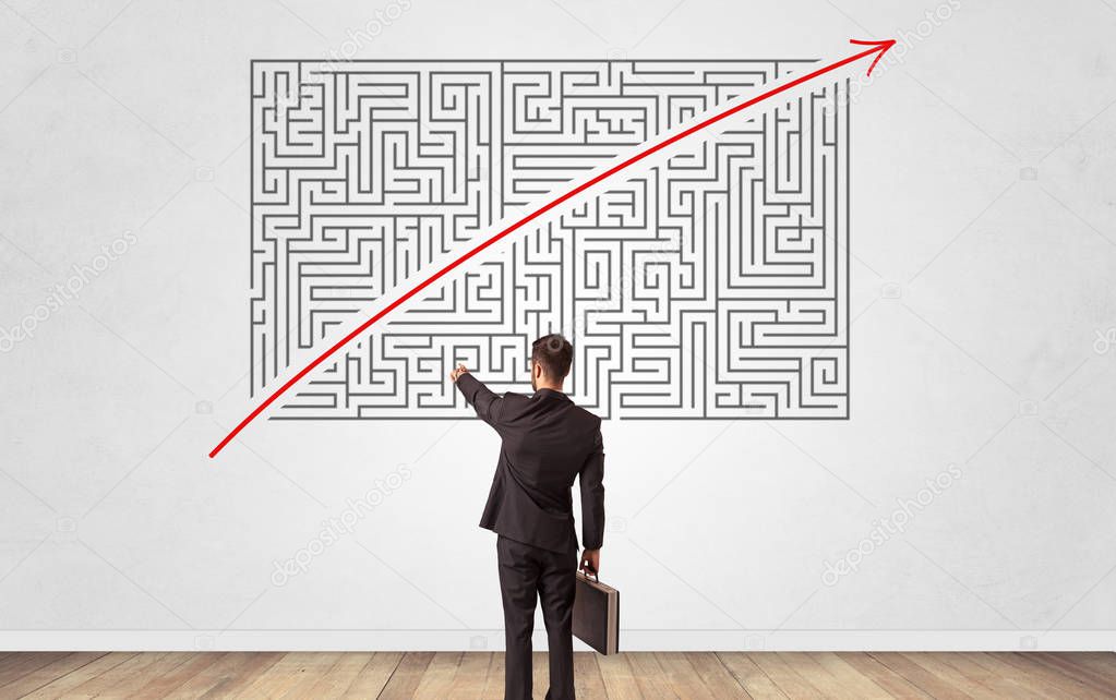 Businessman looking to a maze on a wall