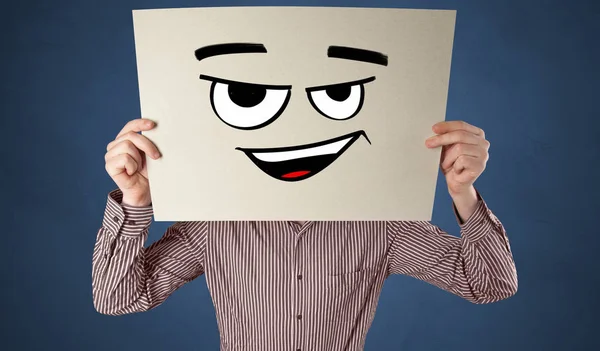 Πρόσωπο που κατέχει ένα χαρτί μπροστά από το πρόσωπό του με doodle φατσούλα — Φωτογραφία Αρχείου