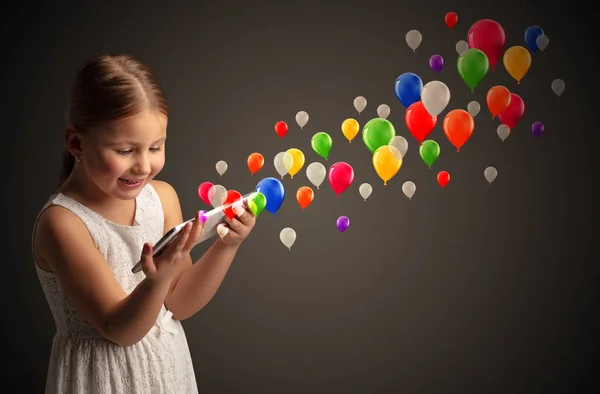 Menina segurando comprimido com balões coloridos ao redor — Fotografia de Stock