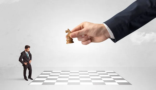 Маленький бізнесмен грає в шахи з концепцією великої руки — стокове фото