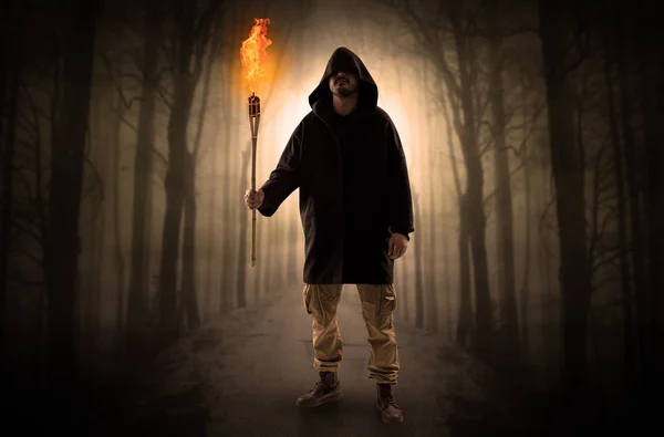 Man coming from dark forest with burning flambeau in his hand concept — Stock Photo, Image