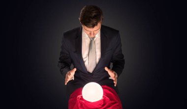 Handsome businessman with magic ball and dark empty background clipart