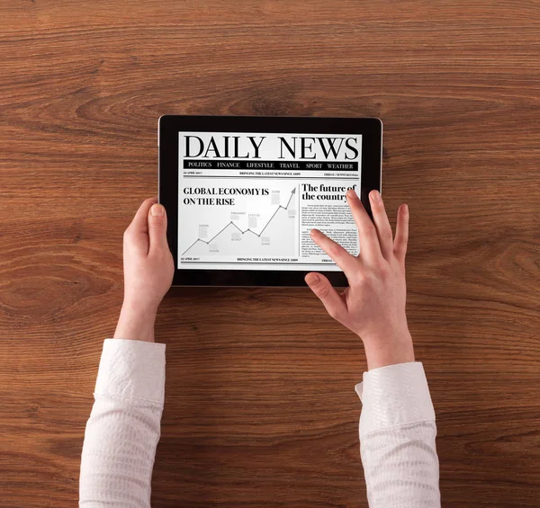 Hand with tablet reading news