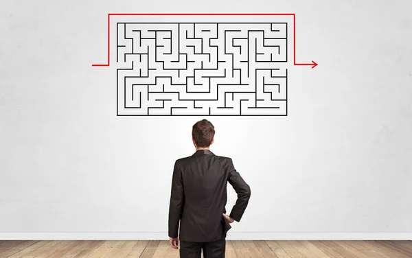 Businessman looking to a maze on a wall — Stock Photo, Image
