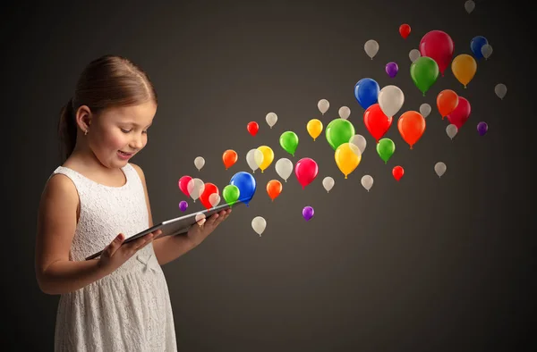 Meisje bedrijf tablet met kleurrijke ballonnen rond — Stockfoto