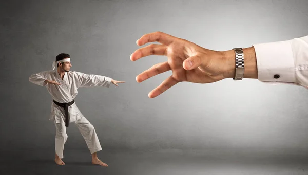 Big hand catching small karate man — Stock Photo, Image