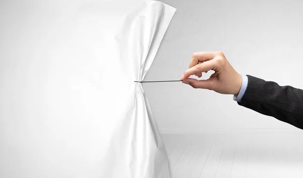 Рука тянет белый занавес бумаги — стоковое фото