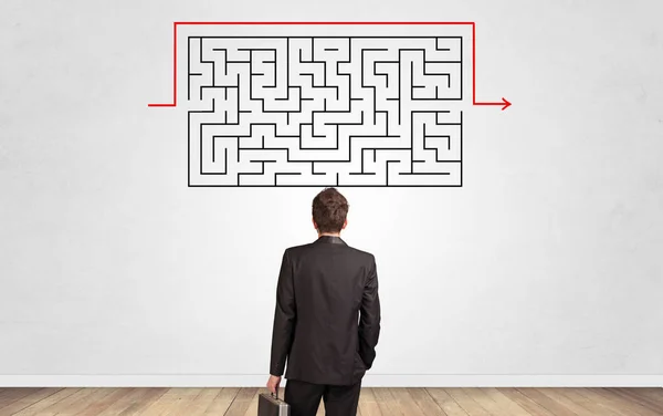 Geschäftsmann blickt auf ein Labyrinth an einer Wand — Stockfoto
