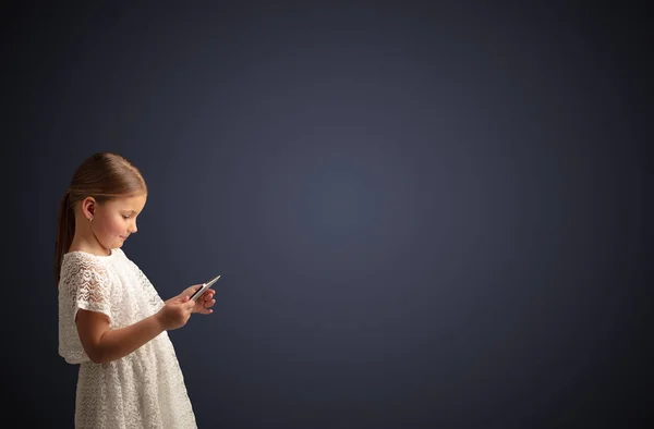 Nettes kleines Mädchen mit Tablet mit dunklem Hintergrund — Stockfoto