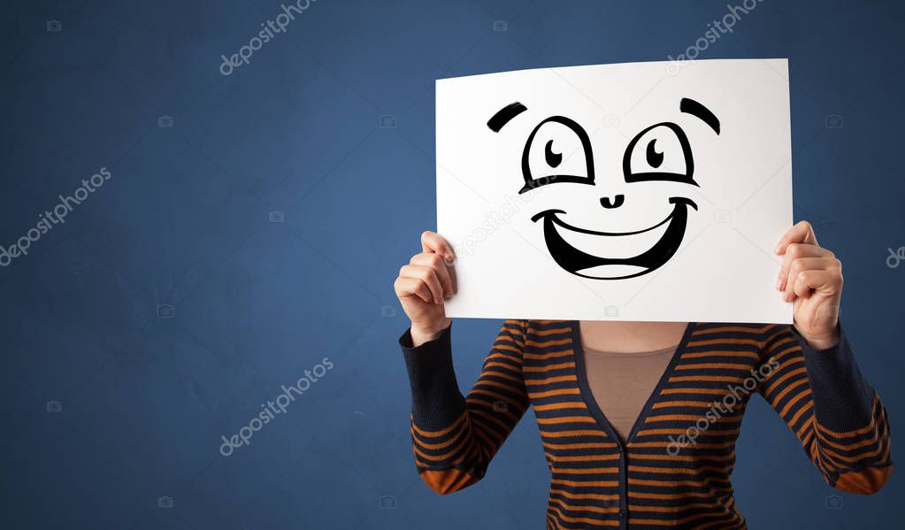 Person holding a paper in front of his face with doodle emoticon