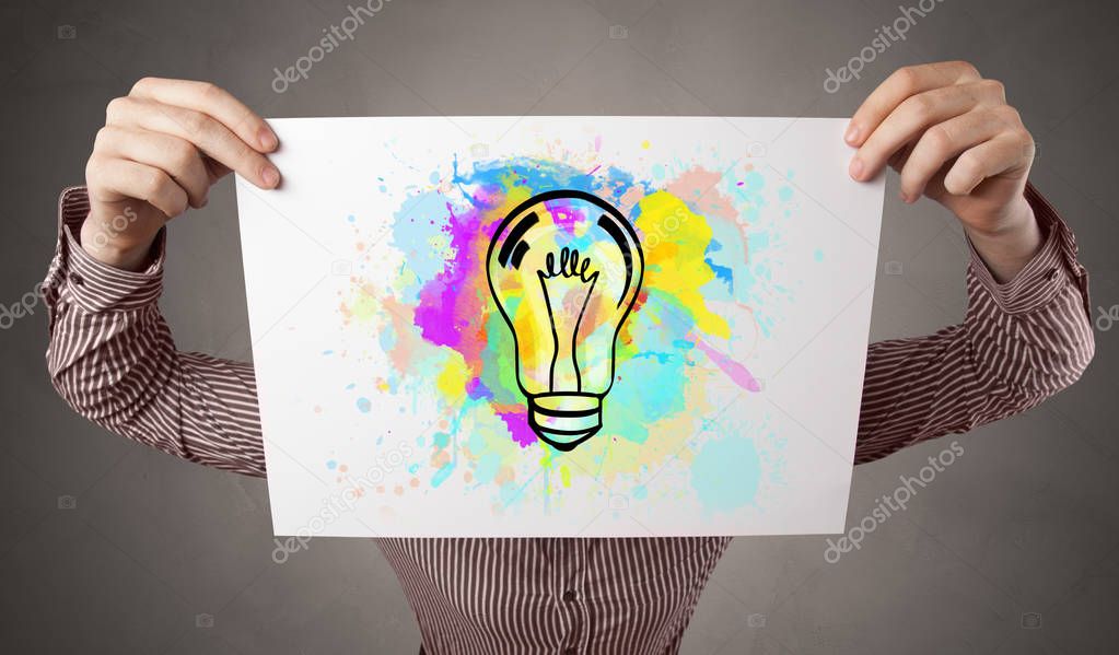 Person holding a paper with colorful bulb concept