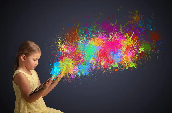 Menina segurando comprimido com respingo colorido ao redor — Fotografia de Stock