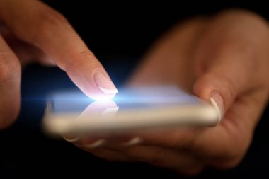 Koyu arka plan ile telefon dokunmak parmak