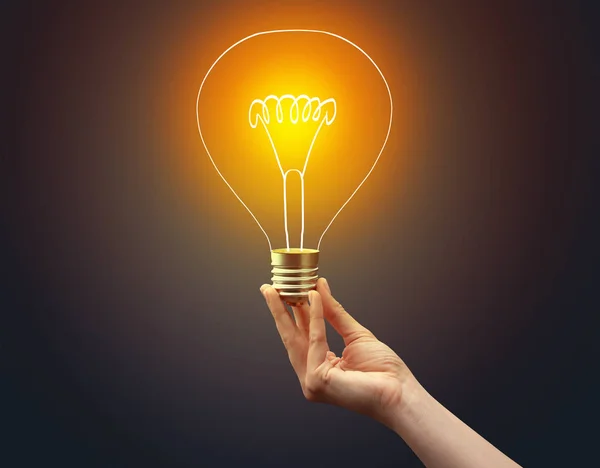 Hand holding light bulb on dark background — Stock Photo, Image