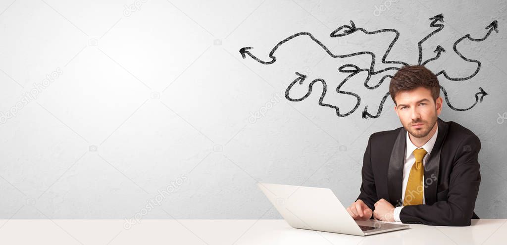 Businessman sitting at desk with arrows around