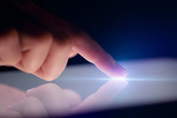 Prst dotýká tablet s tmavým pozadím — Stock fotografie