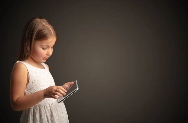 Cute little girl using tablet with dark background Royalty Free Stock Photos