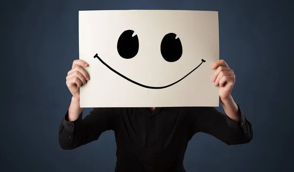 Person holding a paper with funny emoticon in front of her face — Stock Photo, Image