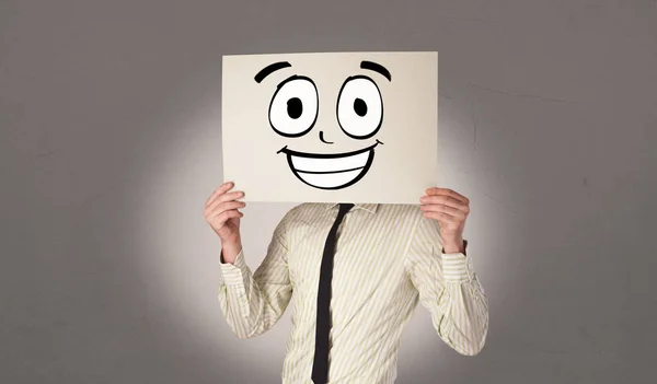 Studenten houden een papier met lachende emoticon voor zijn gezicht — Stockfoto