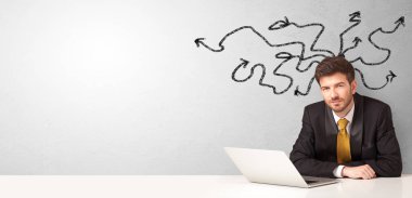 İş adamı etrafında oklar ile masada oturuyor