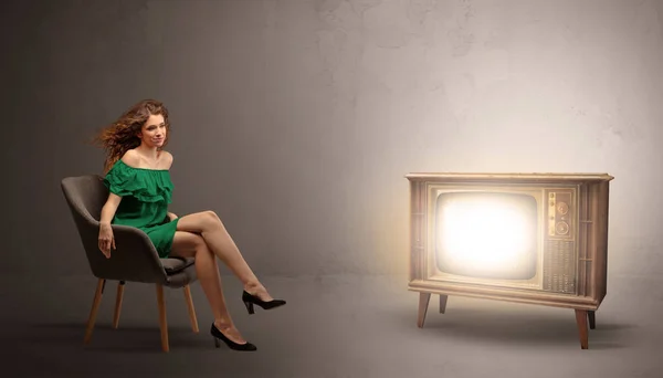 Junge Frau schaut auf einen alten Fernseher — Stockfoto