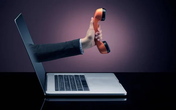 Mão com telefone saindo de um laptop — Fotografia de Stock