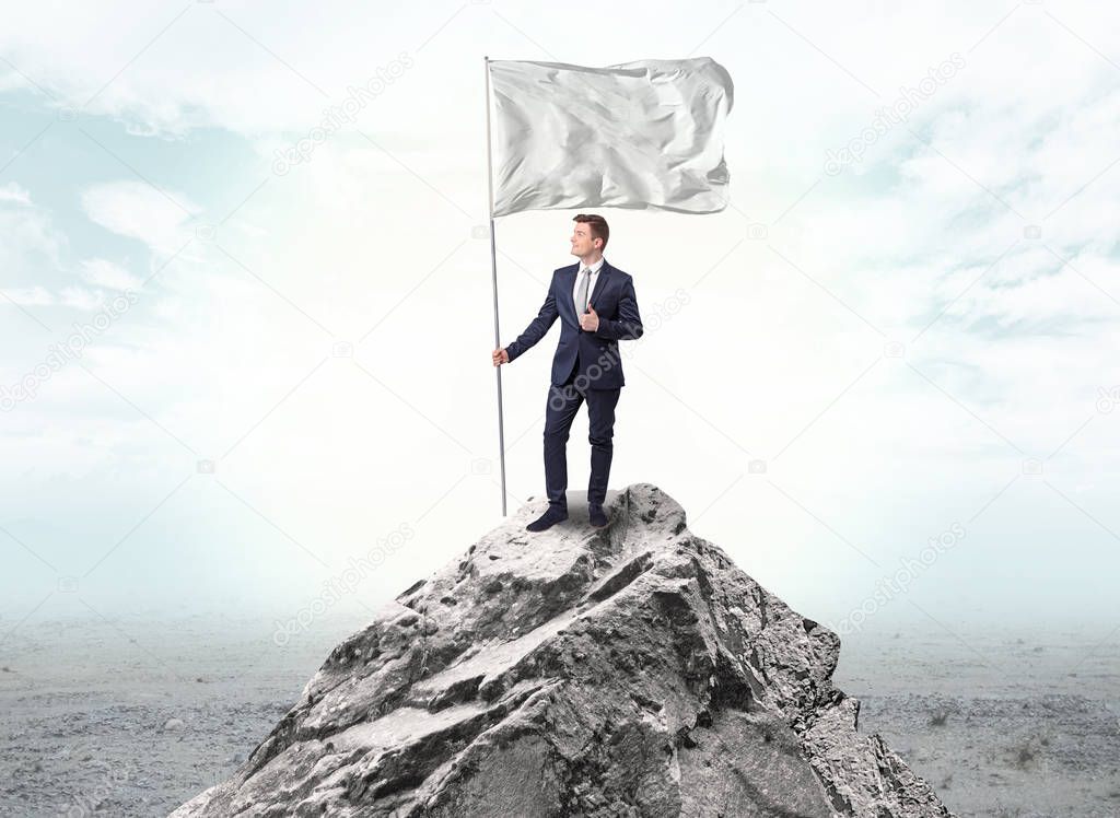 Businessman on the top of a the mountain holding flag